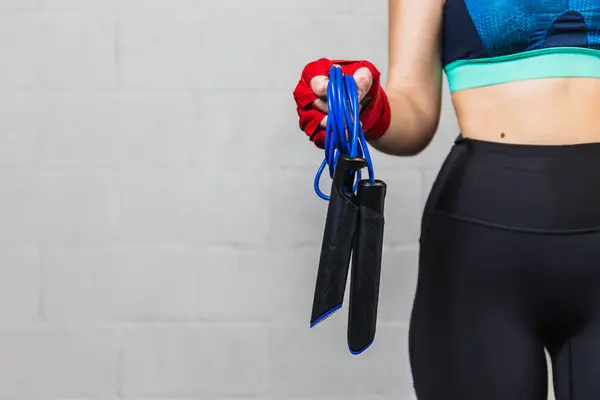 Horizontal photo horizontal girl teen caucasian, dressed in sportswear, with red bandages on her hands and a skipping rope. Training in a boxing gym. Copy space. Concept sports, recreation.