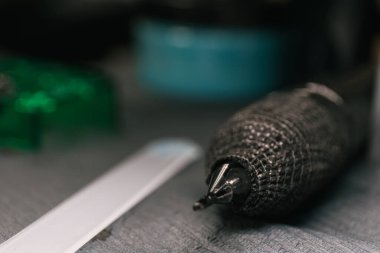 Yatay fotoğraf. Detaylı dokuları olan bir dövme makinesi. Gri bir yüzey üzerinde dinleniyor. Uzayı kopyala İş dünyası, sanat.