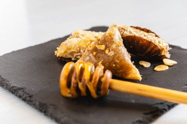 Hassas bir şekilde bal serpiştirilmiş ve bademlerle serpiştirilmiş nefis Arap hamur işleri, şık bir servis tahtasında sunuluyor. Gıda ve kültür konsepti.