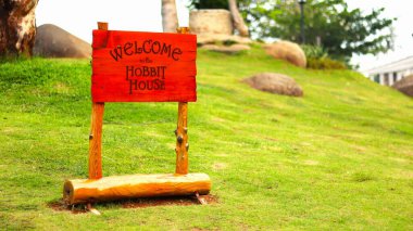 Hobbit house sign with a red handle on a green grass