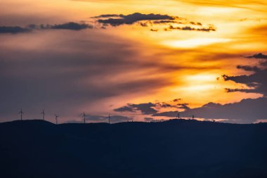 Trakya 'daki Ulusal Park Delta Evros yakınlarındaki dağda rüzgar türbinleri, günbatımı renkleri.