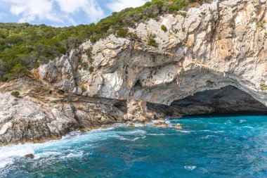 Explore the Meganisi Papanikolis Sea Cave in Lefkada island Greece, near Nydri on a boat cruise, blue sky and waves. clipart