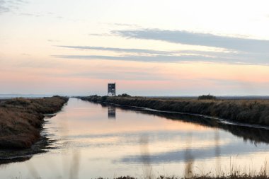 Yunanistan Dedeağaç yakınlarındaki Evros Deltası Ulusal Parkı 'nda gün batımı veya gün doğumu, kuş gözlemevi yansıması.