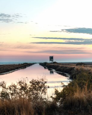 Yunanistan Dedeağaç yakınlarındaki Evros Deltası Ulusal Parkı 'nda gün batımı veya gün doğumu, kuş gözlemevi yansıması.