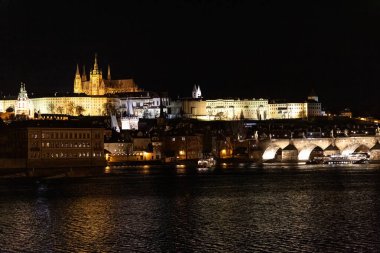 Prag Tarihi Gotik Ortaçağ Kalesi, St. Vitus Katedrali, Charles Köprüsü ve Vltava Nehri tekne turu, astronomik saat, Unesco şehir turizmi, gece görüş ve su yansıması.
