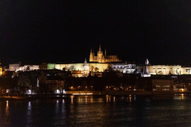 Prag Tarihi Gotik Ortaçağ Kalesi, St. Vitus Katedrali, Charles Köprüsü ve Vltava Nehri tekne turu, astronomik saat, Unesco şehir turizmi, gece görüş ve su yansıması.