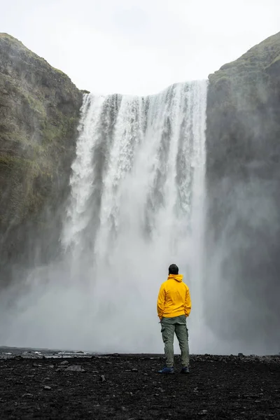 Guy in Yellow jumper watching Skogafoss