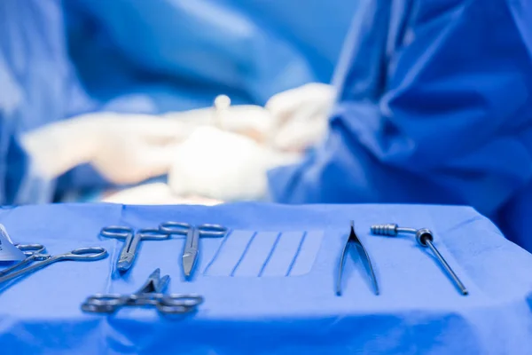 Close up photo of surgeon \'s hands inside modern operating room in blue surgical gown suit with blur background.Scrub nurse send surgical instrument to surgeon in key hole surgery.Medical concept.