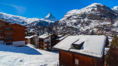 View of famous Swiss Alps ski resort,Matterhorn snow mountain peak in background.Winter travel and winter landscape.Blue sky in sunny day in mid winter.Zermatt,Switzerland.Wooden cottage ski hotel.