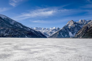 Frozen lake in the middle of cold winter in northern China.Blue sky winter.Mountain in the background and frozen lake foreground.Winter landscape at Yilhun tso in Tibet.