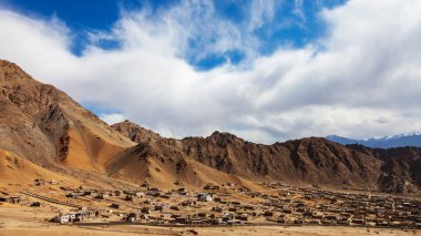 Panorama landscape of village in dessert territory. The countryside of Leh Ladakh, India. Blue sky with clouds. A small village with a mountain in the background.