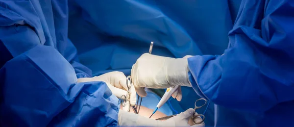 Panorama banner inside operating room.Doctor and team of nurse doing surgery inside a theatre in hospital.Orthopedic spine surgery with medical instrument.Surgeon in blue sterile uniform in close up.