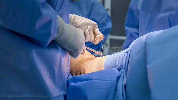 Doctor in blue uniform do surgery inside operating room in orthopedic hospital.Surgeon made suture on skin.Surgeon hold medical equipment to do surgery in operating theatre with space.Medical concept.