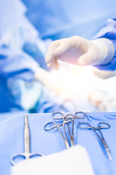病院の手術室内の外科用クランプ医療機器 クランプ機器に焦点を当てます 外科医の手は光効果でデバイスをピックアップし 背景をぼかす — ストック写真
