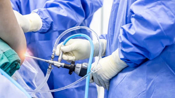 Team of doctor did arthroscopic orthopedic shoulder surgery inside operating room in hospital in blue uniform.Hand of surgeon holding camera in rotator cuff keyhole surgery.Endoscopic technology.
