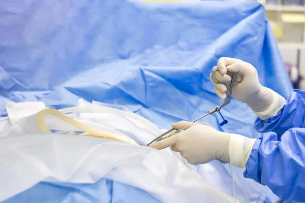 Doctor or surgeon in blue gown did endoscopic spine surgery inside orthopedic operating room with blur background.People use medical instrument for discectomy in keyhole spinal surgery.hand of surgeon