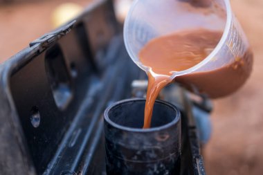 Bina inşaatında su kalitesi testi. İnşaat işi. Suyun bulanık arkaplandaki asitliğini ölçmek için test cihazına veya ekipmana kahverengi renkli su dökülüyor.