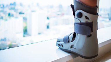 Bulanık şehirli ya da şehir planlı ortopedik yürüyüş botları. Ayak bileği kırığı olan iş adamı ya da kadın. Tıbbi ve sigorta konsepti. Ofisteki işçiye tazminat..