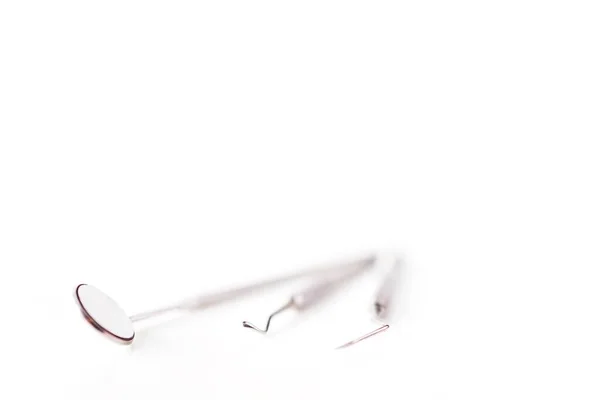 Hastanedeki diş sağlığı kliniğinde beyaz bulanık arka planda izole edilmiş diş aleti veya ekipmanların kapatılması. Diş macunu aynası, Gigival ayırıcı ve diş ağrısı veya ortodontik sonda..