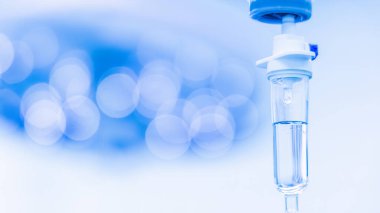 Geçmişinde bulanıklık olan mavi şırınga pompası. Doktorun ameliyat sırasında ameliyathanede kullandığı damar içi sıvı. Arka planda cerrahi lamba..