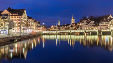 Tarihi Zürih kenti İsviçre 'nin Limmat nehri ile gece manzarası. Tarihi Zürih şehir merkezinin panoramik manzarası ünlü Fraumunster Kilisesi ve Limmat nehri ile birlikte, alacakaranlık vakti Zürih Gölü' nde..