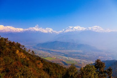 Nepal, Pokhara yakınlarındaki Sarangkot tepesinden Himalayalar 'ın panoramik manzarası. Nepal' in kış mavisi gökyüzü ile renkli manzarası. Panoramada alanı olan bir dağ. Nepal 'de parlak mavi gökyüzü ve karlı..