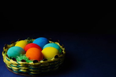 Easter composition. Colorful easter eggs in basket on blue background. The minimal concept. Flat lay. Copy space.
