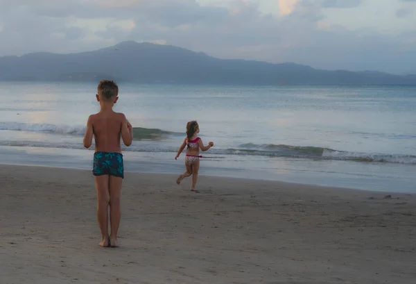 cheerful children playing with sand and sea waves on the beach. Brazil