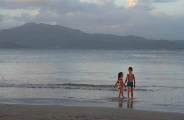 cheerful children playing with sand and sea waves on the beach. Brazil