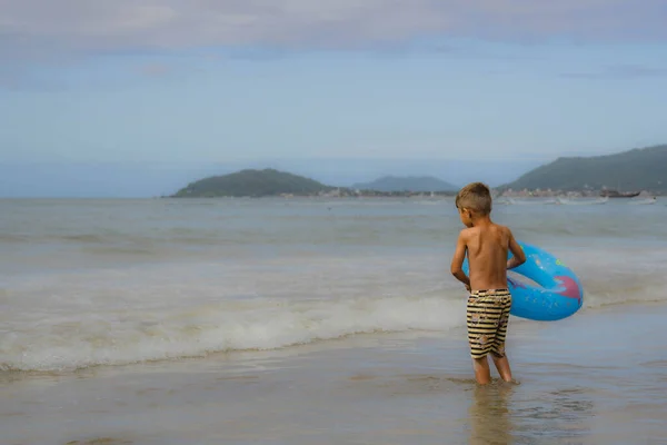 cheerful children playing with sand and sea waves on the beach. Brazil