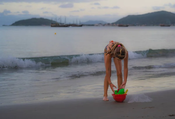 cheerful children playing with sand and sea waves on the beach. Brazil