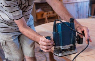 Male carpenter, working in the carpenter's workshop with power h