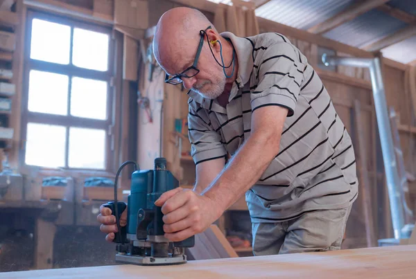 Male carpenter, working in the carpenter's workshop with power h