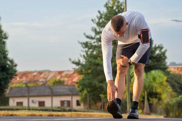 Young male person training, monitoring times with smartphone.