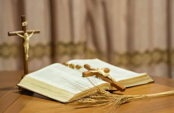 Holy Week religious composition with wooden crucifixion, palm leaf, willow branch, wheat ear. Bible and rosary. Holy week concept, Sunday in copy space.