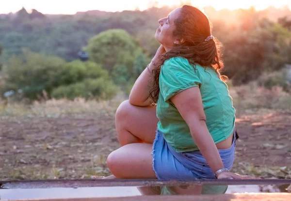 young girl with sun in background talking cheerfully on cell phone
