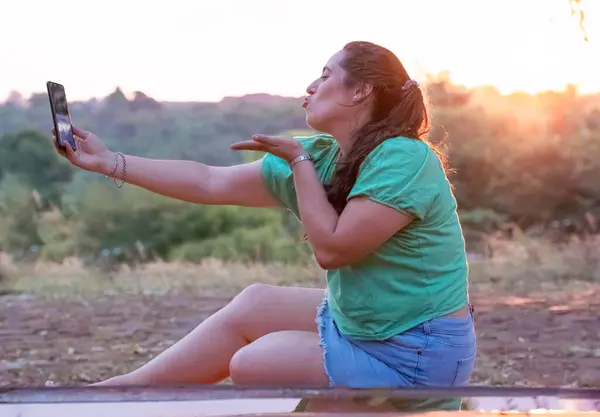 young girl with sun in background talking cheerfully on cell phone