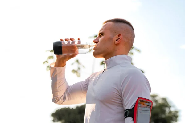 Young male person training, monitoring times with smartphone.