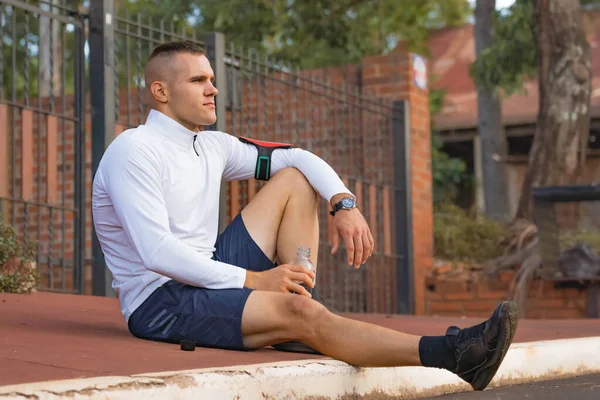 Young male person training, monitoring times with smartphone.