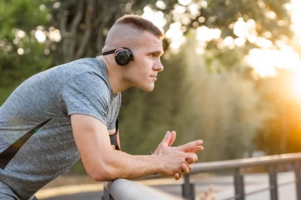 Young male person training, monitoring times with smartphone.