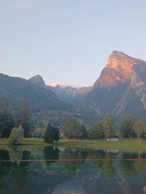 Majestic mountains in Haute-Savoie, France, glowing in the warm light of dusk. Their reflection in the still waters of the lake adds to the harmony of this peaceful, natural setting. Perfect for showcasing alpine serenity clipart