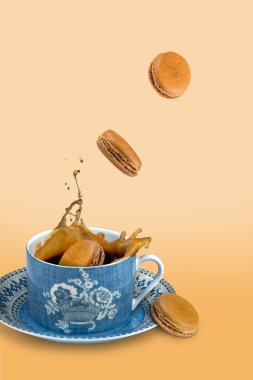 Coffee macaroon being dropped into a cup of coffee on a coffee colored background