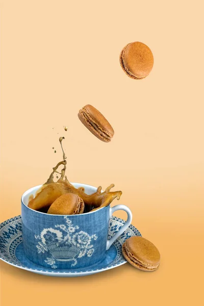 Coffee macaroon being dropped into a cup of coffee on a coffee colored background