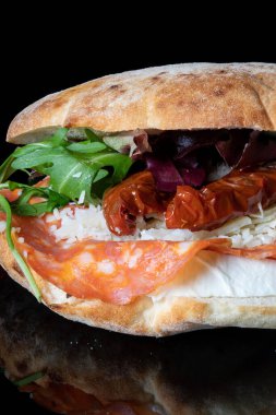 Chorizo, parmesan ve acı biberli sandviçi siyah bir arkaplanda, yansıması olan yakın plan..