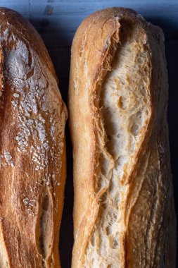 Ekmek kabuğunu ve dokusunu vurgulayan iki baget ekmeği yakın çekim.