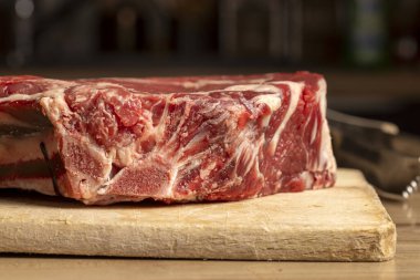 Tahta kesme tahtasındaki çiğ sığır pirzolası şişmanlığı ve mermeri gösteriyor..