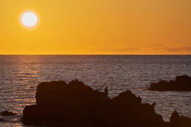 Sado,Japan - October 20, 2022: A lone angler on a rock at sunset at Shukunegi of Sado island, Niigata, Japan