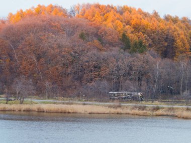 Hokkaido,Japan - Novermber 13, 2024: A Sekihoku line train running along Lake Abashiri, Hokkaido, Japan at sunset clipart