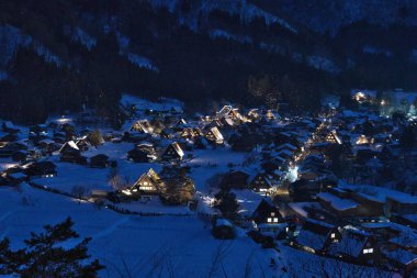 Gifu, Japonya - 19 Ocak 2025: Shirakawago, Gifu, Japonya 'da aydınlatılmış sazdan çatı evleri panoramik görünümü