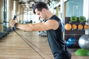 Man pulling cables. Handsome athlete male lifting up and push up on sling to maintain muscle, build strength, flexibility at health club.